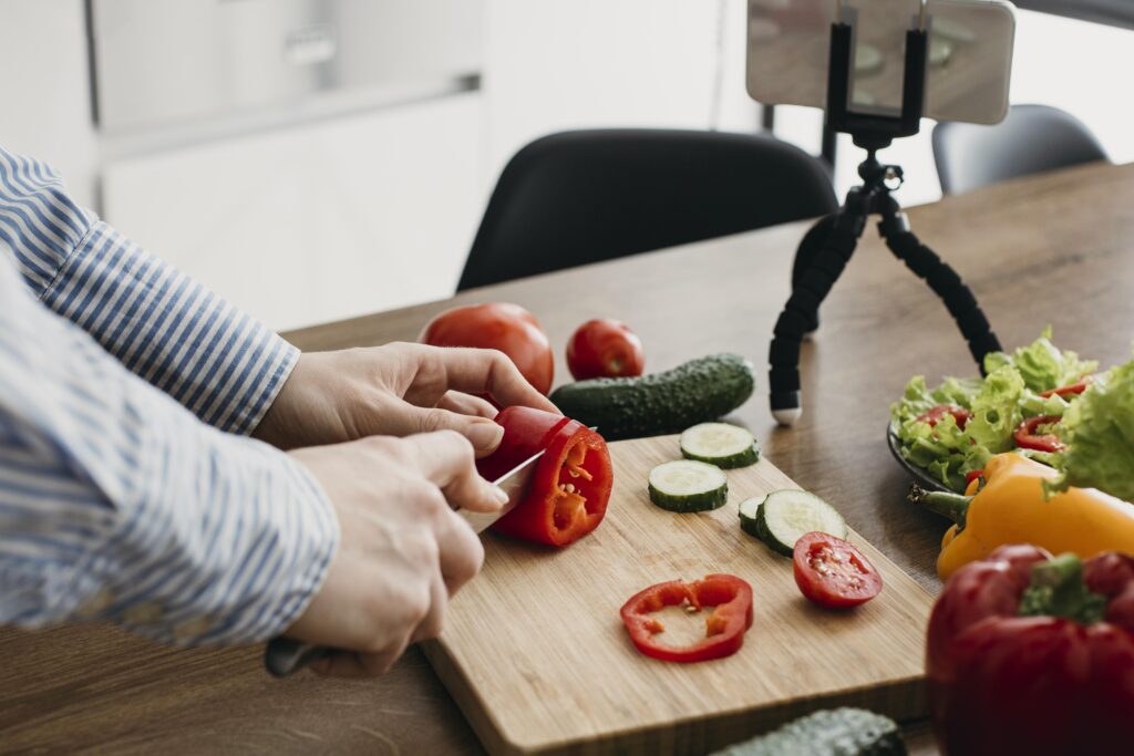 "Female food blogger cooking at home while live streaming with a smartphone, showing precision and ease in the kitchen