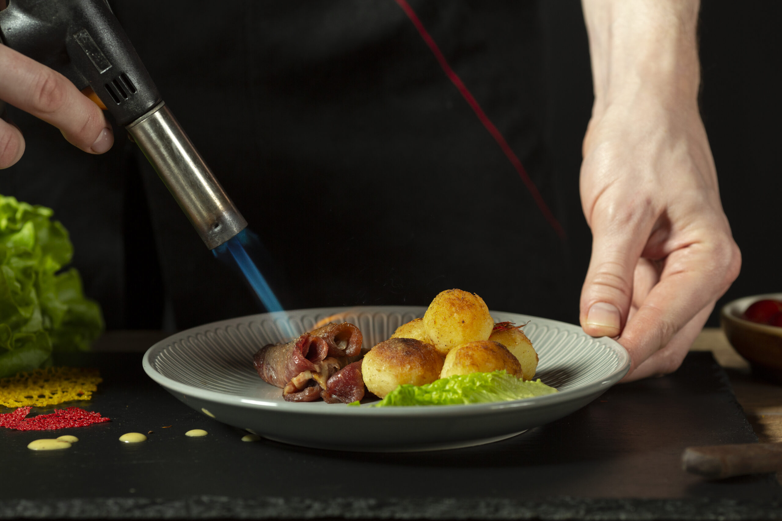 Culinary torch caramelizing sugar on crème brûlée, demonstrating professional kitchen torching techniques for home cooking.